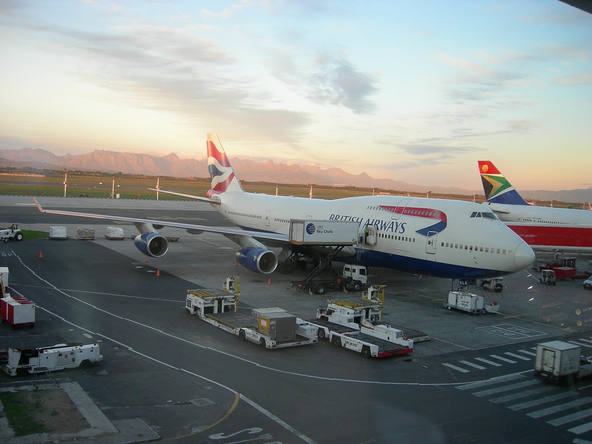 An airliner at Cape Town International at dusk, with mountains beyond